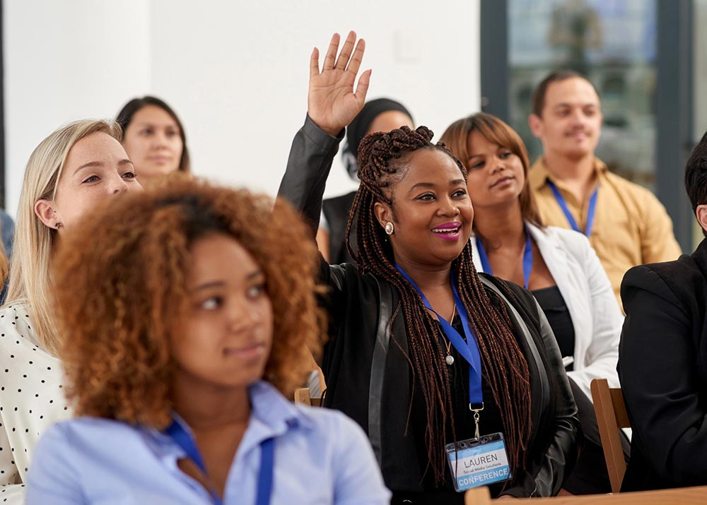 Emerging Leaders course participants with female participant holding hand up for a question